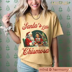 This Santa's Little Chismosa Christmas T-shirt is a perfect holiday gift for Latinas ready for all the chisme, featuring a retro graphic design. The Comfort Colors tee is made with high-quality 100% ring-spun US cotton for long-lasting comfort. The relaxed fit and crew neckline make it versatile for both casual and semi-formal settings, making it perfect for Christmas parties and gift-giving hispanic mamas.  Product features - Available in sizes S to 4XL for a perfect fit - Double-needle stitching for durability - Made with soft, dyed fabric for comfort - Relaxed fit and crew neckline for versatile styling - Ethically grown and harvested 100% US cotton Care instructions - Machine wash: cold (max 30C or 90F) - Do not bleach - Tumble dry: low heat - Iron, steam or dry: low heat - Do not dryc Funny Print Tops For Christmas Gifts, Funny Print Top For Christmas Gift, Funny Print Tops For Christmas Gift, Festive Crew Neck Graphic Print Shirt, Festive Graphic Print Crew Neck Shirt, Christmas Funny Print T-shirt As Gift, Christmas Gift T-shirt With Funny Print, Festive Crew Neck Shirt With Graphic Print, Graphic Print Top As Christmas Gift