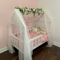 a white crib with pink bedding and flowers on top