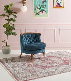 a blue chair sitting on top of a rug in a living room next to a potted plant