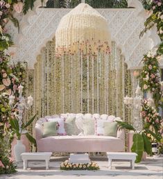 a white couch sitting under a chandelier covered in flowers