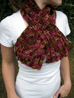 a woman is wearing a crocheted scarf in red and brown colors with a white t - shirt