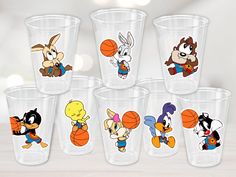 six cups with cartoon characters on them sitting in front of a white background and one has a basketball ball