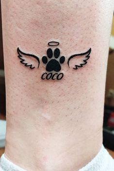 a dog's paw with an angel wing tattoo on the ankle