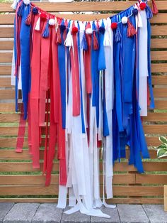 red, white and blue streamers are hanging from a wooden slatted fence