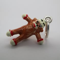 a brown and white dog charm on a silver plated keychain with a red nose ring