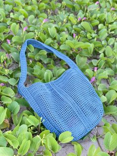 a blue purse sitting on top of green plants