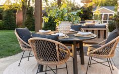 an outdoor table with chairs and plates on it