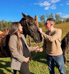 a man standing next to a woman near a horse