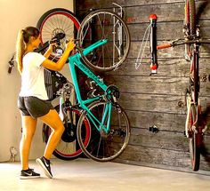 a woman standing in front of a bike next to a wall with bicycles on it