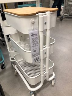 the back of a white cart with three shelves on each side and a wooden cutting board attached to it