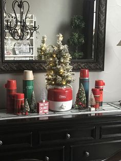 a christmas tree is sitting on top of a dresser in front of a mirror and other holiday decorations