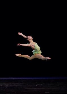 a woman is jumping in the air with her legs spread out and arms extended up