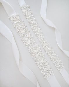 "A statement sash is encrusted with beautiful pearls attached on bridal white double-faced satin ribbon. This classic pearly belts creates a romantic finishing touch to your bridal gown, bridesmaids and flower girls, or as hair accessories.  DETAIL: Adult Size 108\" Kids Size 78\" Headband Size 60\" Applique size: 12\" length, 2\" wide/1.25\" wide - We DO NOT offer refunds.  Selected items are eligible for EXCHANGE ONLY within 14 days of delivery date.   All accessories are FINAL SALE. - We are Elegant Bridal Belt With Satin Bow For Wedding, Elegant White Bride Sashes, Elegant White Bridal Belt With Satin Bow, Wedding Bridal Belt With Sashes In Satin, Elegant White Bridal Belt With Pearl Embroidery, Elegant White Satin Bridal Belt, White Ribbon Bridal Belt For Party, White Crystal Embellished Bridal Sash, Elegant Pearl Embellished Sashes For Party