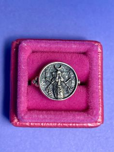 a ring with an image of jesus on it in a pink velvet box, against a blue background