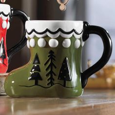 two coffee mugs sitting on top of a counter next to each other with christmas decorations