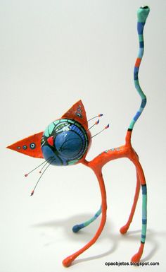 an orange and blue cat figurine is holding a ball on its back legs