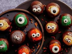 chocolate covered donuts decorated with eyes and sprinkles on a black plate