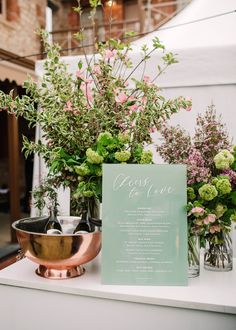 vases filled with flowers sitting on top of a white counter next to a sign