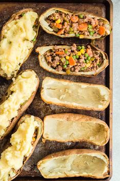 baked potatoes on a baking sheet with meat and vegetables in the middle, ready to be cooked