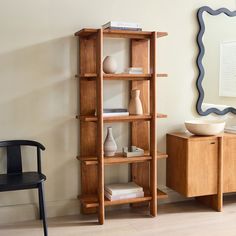 a wooden shelf with books and vases on it in a room next to a mirror