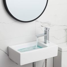 a white sink sitting under a round mirror