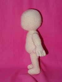 a small white doll standing on a pink surface