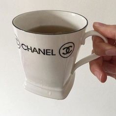 a hand holding a coffee cup with the logo of chanel on it, in front of a white background