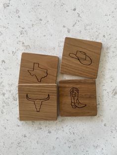 four wooden coasters with drawings of cowboy hats on them