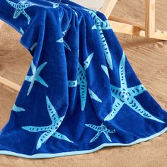 a blue towel with starfishs on it sitting on a beach chair next to the ocean