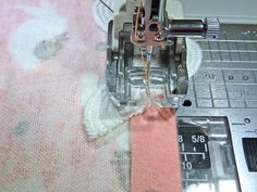 the sewing machine is working on the pink and white fabric that has been sewn