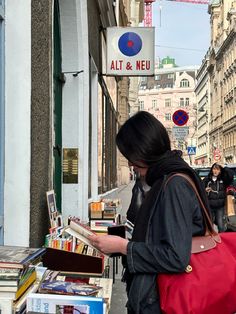 a woman is looking at books on the sidewalk