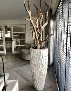 a large white vase sitting on top of a wooden floor next to a living room