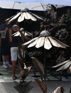 some people are standing around with umbrellas and flowers in front of them on display