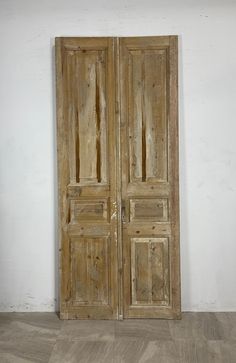 an old pair of wooden doors sitting on top of a hard wood floor next to a white wall