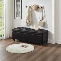 a black bench sitting on top of a hard wood floor next to a white rug