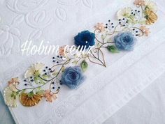 blue and white flowers are embroidered onto a white tablecloth