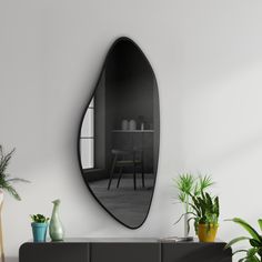 a mirror on the wall above a table with potted plants