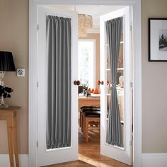 an open door leading to a dining room with curtains on the outside and inside doors