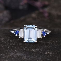 an aquamarine and white topazte ring with three blue sapphires on it