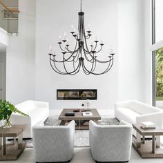 a living room filled with white furniture and a chandelier hanging from the ceiling