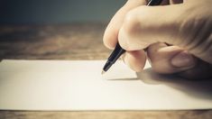 a person is writing on a piece of paper with a pen in their left hand