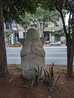 there is a large statue in the middle of the ground next to some trees and plants