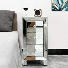 a bedroom with a bed, mirror cabinet and wine glass on the nightstand next to it