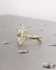 a close up of a diamond ring on a surface with drops of water around it