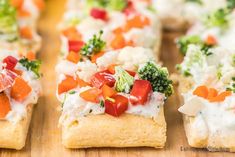 small appetizers with vegetables and cheese on them are arranged on a cutting board