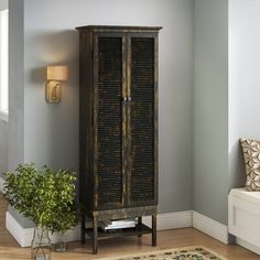 a tall wooden cabinet with shutters on the front in a living room next to a couch