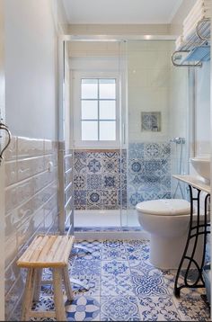 a bathroom with blue and white tiles on the floor, shower stall and sink area