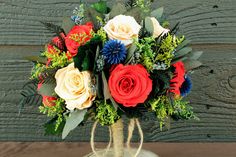 a vase filled with red, white and blue flowers on top of a wooden table