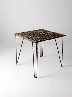 a small table with hairpin legs and a square design on the top is shown in front of a white background