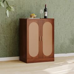 a wooden cabinet with two doors and a wine bottle on top, in front of a green wall